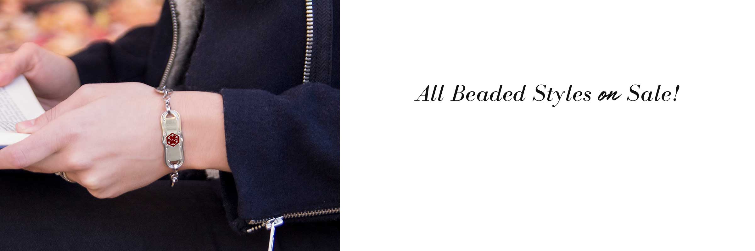 Woman holding cup of tea on plaid blanket wearing medical ID tag with decoration and red symbol