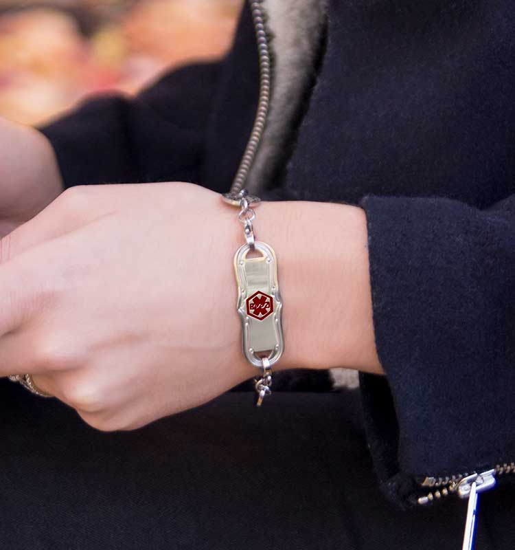 Woman wearing medical ID bracelet with decorative medical ID tag holding cup of tea