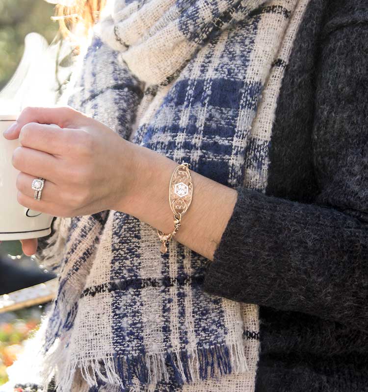 Woman wearing medical ID bracelet with decorative medical ID tag holding cup of tea
