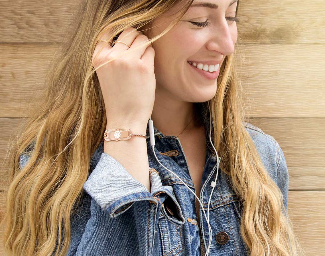 Smiling woman wearing jean jacket and rose gold medical alert bracelet