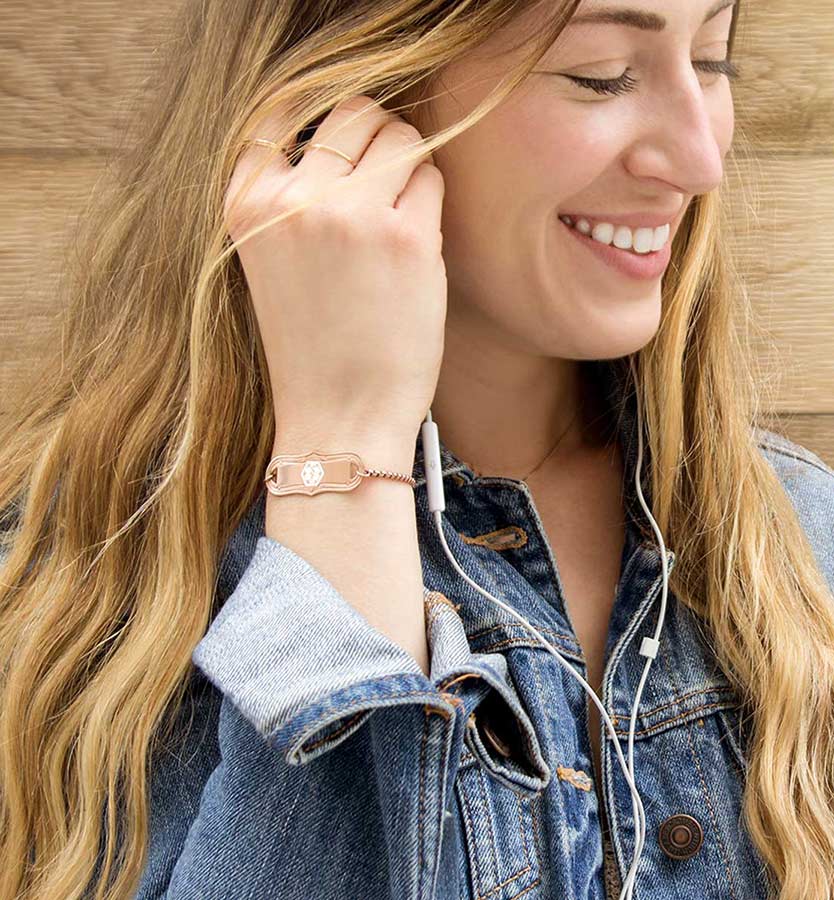 Smiling woman wearing jean jacket and rose gold medical alert bracelet