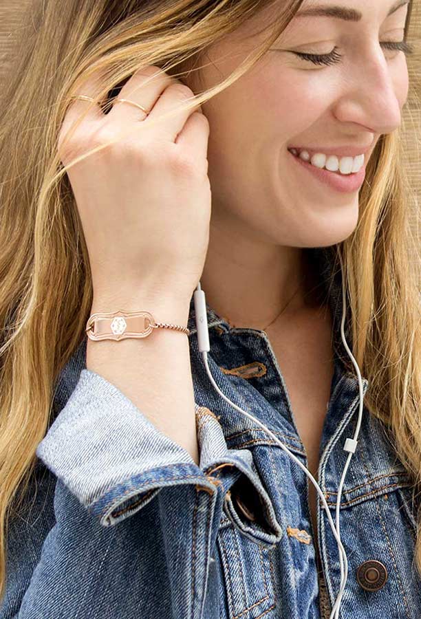 Smiling woman wearing jean jacket and rose gold medical alert bracelet